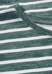 Zielono-biała, pasiaste tkanina o miękkiej fakturze. Posiada zaokrąglony dekolt z prążkowanym wykończeniem. Poziome paski różnią się szerokością.