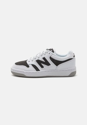Sneaker bianco e nero con tomaia in pelle, dettagli perforati, accenti testurizzati e suola in gomma. Presenta un logo sulla linguetta.