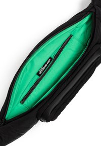 Zwarte gevoerde tas met een levendige groene binnenkant. Bevat een hoofdvak met rits en een binnenvak met een etiket. Gecoate textuur.