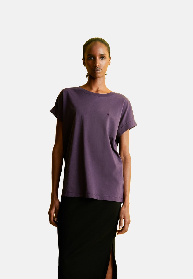 Paarse korte mouwen t-shirt van zacht stof, met een ontspannen pasvorm en een kleine geborduurde accent op de borst, gecombineerd met een zwarte rok.