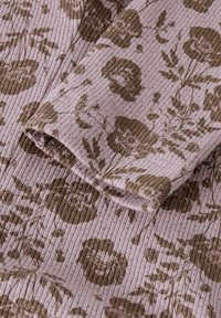 Gros plan sur un tissu mauve côtelé avec un imprimé floral marron comprenant des fleurs semblables à des coquelicots et des feuilles, montrant des coutures détaillées et la texture.