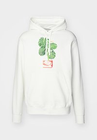 Vit hoodie med en grön monstera-växtgrafik ovanför en röd Nike-logotypruta på framsidan, med dragsko och en framficka.