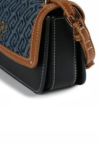 Borsa in tessuto blu con motivo, rifiniture in pelle color cuoio e lati neri. Caratterizzata da cuciture bianche e una targhetta con logo dorata. Tracolla regolabile inclusa.