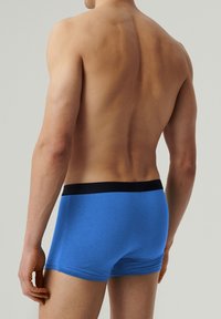 Niebieskie bawełniane bokserki z czarnym elastycznym pasem, charakteryzujące się przylegającym krojem i gładką fakturą, widziane z tyłu.