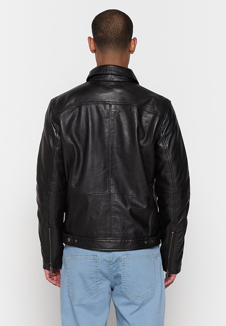 Giubbotto in pelle nera con design strutturato, dotato di colletto, cuciture in vista e tasche laterali con zip. La vista posteriore mette in evidenza linee pulite.