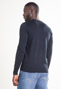 Maglione in maglia blu navy con polsini e orlo a coste, caratterizzato da un classico scollo rotondo. Il tessuto appare liscio con una texture minima.