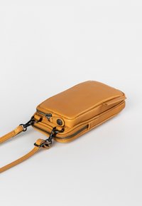 Compact mustard-yellow leather crossbody bag with a zip closure, adjustable strap, and smooth texture. Features visible hardware accents.