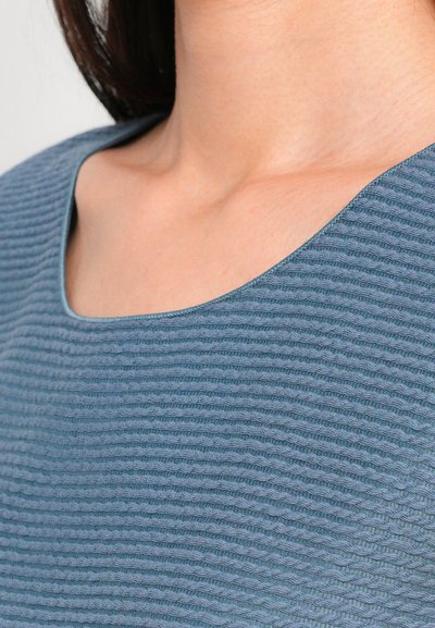 Textured blue top featuring a scoop neckline and ribbed detailing, emphasizing soft fabric with a subtle sheen.