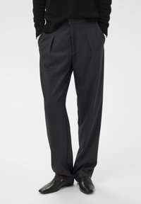 Grijze geplooide broek van een lichtgewicht stof met een relaxte pasvorm. Past goed bij gepolijste zwarte schoenen.