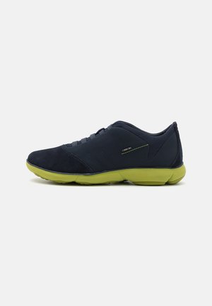 Navy suede athletic shoes with a textured finish, green rubber sole, and lace-up design, featuring subtle reflective accents on the side.