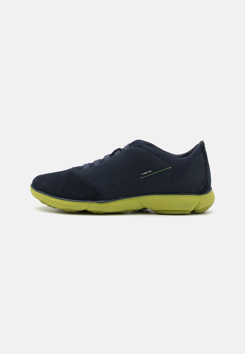 Scarpe da ginnastica blu in pelle scamosciata con finitura texture, suola gommata verde e design lacciato, con sottili dettagli riflettenti ai lati.