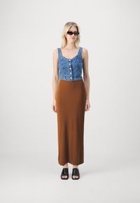 Top corto in denim con dettagli a bottone, abbinato a una gonna maxi ribout color marrone e mule aperti neri. Design semplice e moderno.