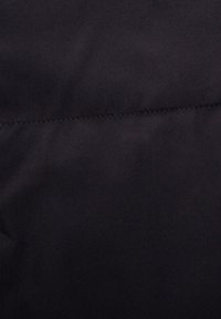 Tessuto nero con una texture liscia e una leggera lucentezza, con una cucitura orizzontale e una rifinitura fine.