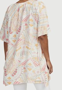 Lätt, mönstrad tunika med lös passform. Har geometriska mönster i orange, rosa och grönt på en vit bakgrund. Kortsleeves.