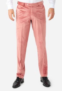 Pantalones de terciopelo rosa con una textura suave, corte ajustado y un solo pliegue, combinados con zapatos negros brillantes.
