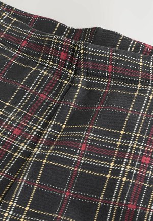Tissu noir avec un motif à carreaux rouge, jaune et blanc. Présente une taille élastique et une surface texturée. Vue en gros plan.
