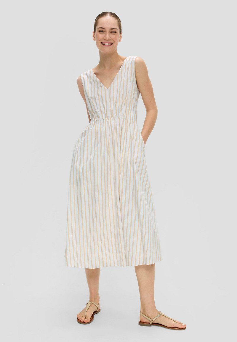 Robe sans manches, longue jusqu'aux genoux, de couleur blanche avec des rayures bleu clair et dorées, dotée d'un col en V, d'une taille élastique et de poches latérales.