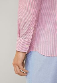 Striped shirt: pink and white vertical stripes, single button cuff, lightweight fabric. Light blue striped pants, soft texture, visible pocket.