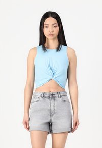 Ανοιχτό μπλε, αμάνικο crop top με σχέδιο στριφτού μπροστά, συνδυασμένο με ανοιχτό γκρι, ψηλόμεσα τζιν σορτς με γυρισμένα χείλη.