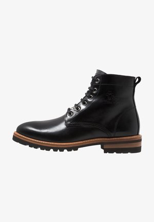 Stivali alla caviglia in pelle nera con finitura liscia, punta tondeggiante, otto occhielli in metallo, dettagli in pelle marrone e suola in gomma testurizzata.