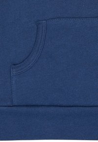 Sezione felpa blu navy con tasca a canguro cucita e orlo a coste, realizzata in un tessuto morbido e testurizzato.