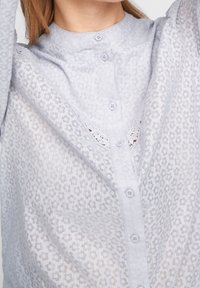 Camicia button-up di un delicato lavanda, caratterizzata da un motivo floreale testurizzato, bottoni di dimensioni ridotte e un classico design del colletto.