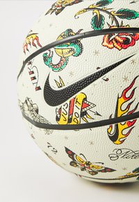 Nike basketball med en struktureret hvid overflade prydet med farverige tattoo-inspirerede grafikker, sorte accenter og et fremtrædende logo.