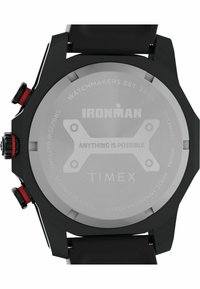 Black stainless steel watch with red accents, featuring a textured case back engraved with brand name and specifications. Water resistant to 100m.