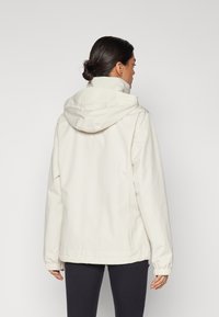 Lys beige hettegenser med elastiske mansjetter og fald. Glatt, teksturert stoff, designet for en løs passform, med en ryggskjorte.