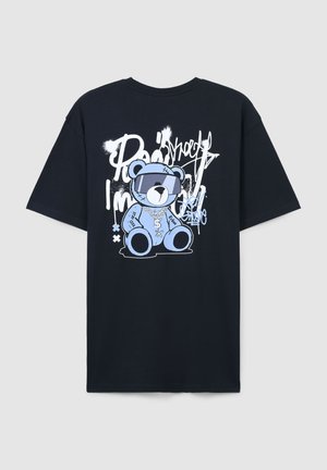 T-shirt in cotone nero con grafica di un orso blu che indossa occhiali da sole e una catena, con testo e accenti in stile graffiti bianchi.