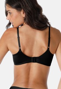 Reggiseno nero caratterizzato da un tessuto liscio, spalline regolabili e una chiusura a gancio e occhiello tradizionale sul retro. Design semplice senza motivi.