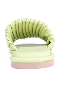 Sandalia plana de cuero verde con una correa drapeada y una suela suave de color rosa claro. Diseñada con una forma minimalista y un contraste de texturas.