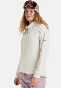 Jasnopłowy polarowy pulower z wysokim kołnierzem, sznurkiem do ściągania i fakturowanym wzorem. W zestawie różowa dziana czapka i gogle narciarskie.