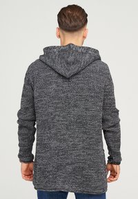 Gray knit hoodie featuring a textured pattern, long sleeves, and a drawstring hood. The back has a straight cut with a longer hem.