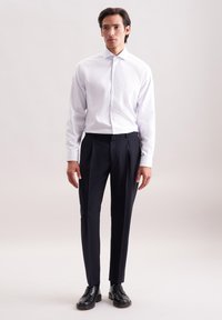 Camicia bianca con righe verticali azzurro chiaro, maniche lunghe e colletto button-down, abbinata a pantaloni navy scuri e scarpe eleganti nere.