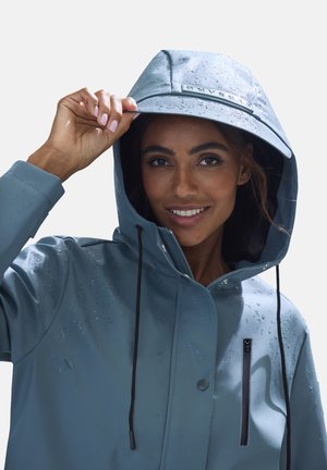 Water-repellent, light blue jacket with a hood. Features a front zip pocket, drawstrings, and water droplets on the surface.