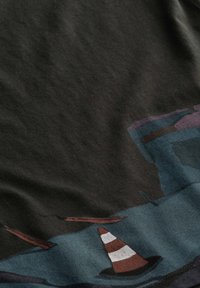 T-shirt nera in cotone con un design grafico che presenta un cono a strisce marroni e bianche e forme astratte in blu e marrone.