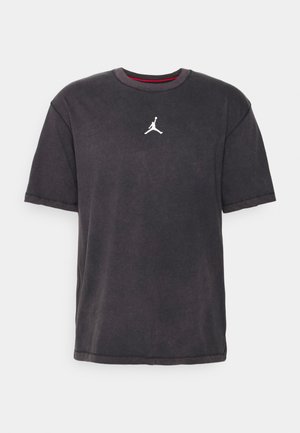 Schwarzes T-Shirt mit kurzen Ärmeln mit einem kleinen weißen Jumpman-Logo in der Mitte der Brust und einem roten Detail im inneren Kragen.