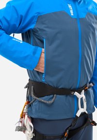 Blaue und graue Wandjacke mit einer Reißverschlusstasche, verstellbaren Bündchen und einem Klettergeschirr. Sie zeichnet sich durch langlebigen Stoff und funktionale Designdetails aus.