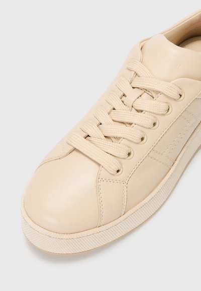 Baskets en cuir beige avec bout arrondi, fermeture à lacets plats, semelle en caoutchouc texturé et coutures latérales discrètes. Comprend des lacets tissés et un intérieur doux.