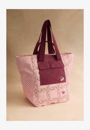 Roosa kott maasika mustritega, tumeroosa eesmine tasku ja sobivad sangad neutraalse tausta vastu.