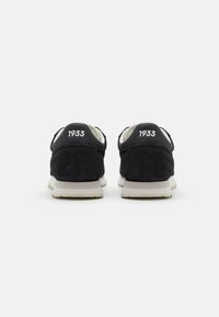 Black suede sneakers with a white sole and padded collar feature "1933" printed on the back. Simple design and classic shape.