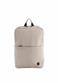 Ljusbeige ryggsäck gjord av mjukt material, med en framficka, svart dragkedja och handtag på toppen för enkel transport. Slät yta.