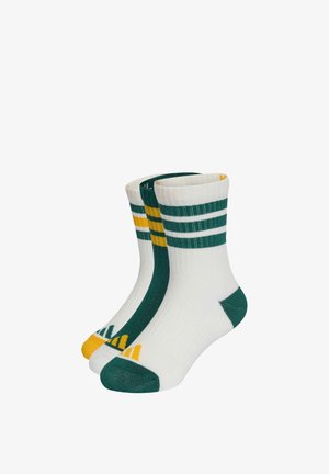 Trois paires de chaussettes blanches montantes avec des orteils et talons verts, des rayures vertes et jaunes en haut, et de petits motifs triangulaires sur les orteils.