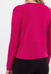 Maglione attillato fucsia con maniche lunghe e scollo rotondo. Texture morbida con orlo a coste e design sul retro.