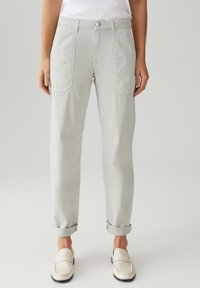 Pantaloni grigi chiari con una vestibilità rilassata, dotati di tasche frontali, risvolti e chiusura con bottone. Tessuto liscio con una leggera lucentezza.