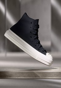 Hohe Sneaker aus navy Gummi mit einer weißen Sohle, ausgestattet mit Schnürsenkeln, einer strukturierten Zehenkappe und einer glatten Oberfläche.