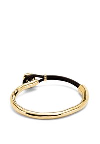 Chouchou en métal doré avec une barre incurvée irrégulière et un élastique noir, maintenu par une petite perle en or.