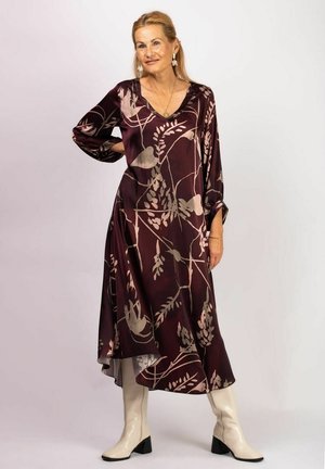 Flowing burgundy dress with brown floral patterns, V-neck, long sleeves, and asymmetric hem, paired with knee-high cream boots.