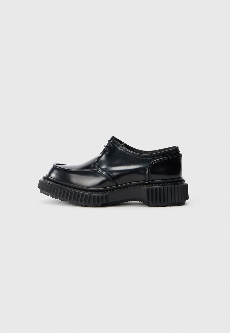 Schwarze Lederschuhe mit abgerundeter Zehenpartie, niedrigem Design und robuster Gummisohle mit tiefen Rillen für besseren Halt.